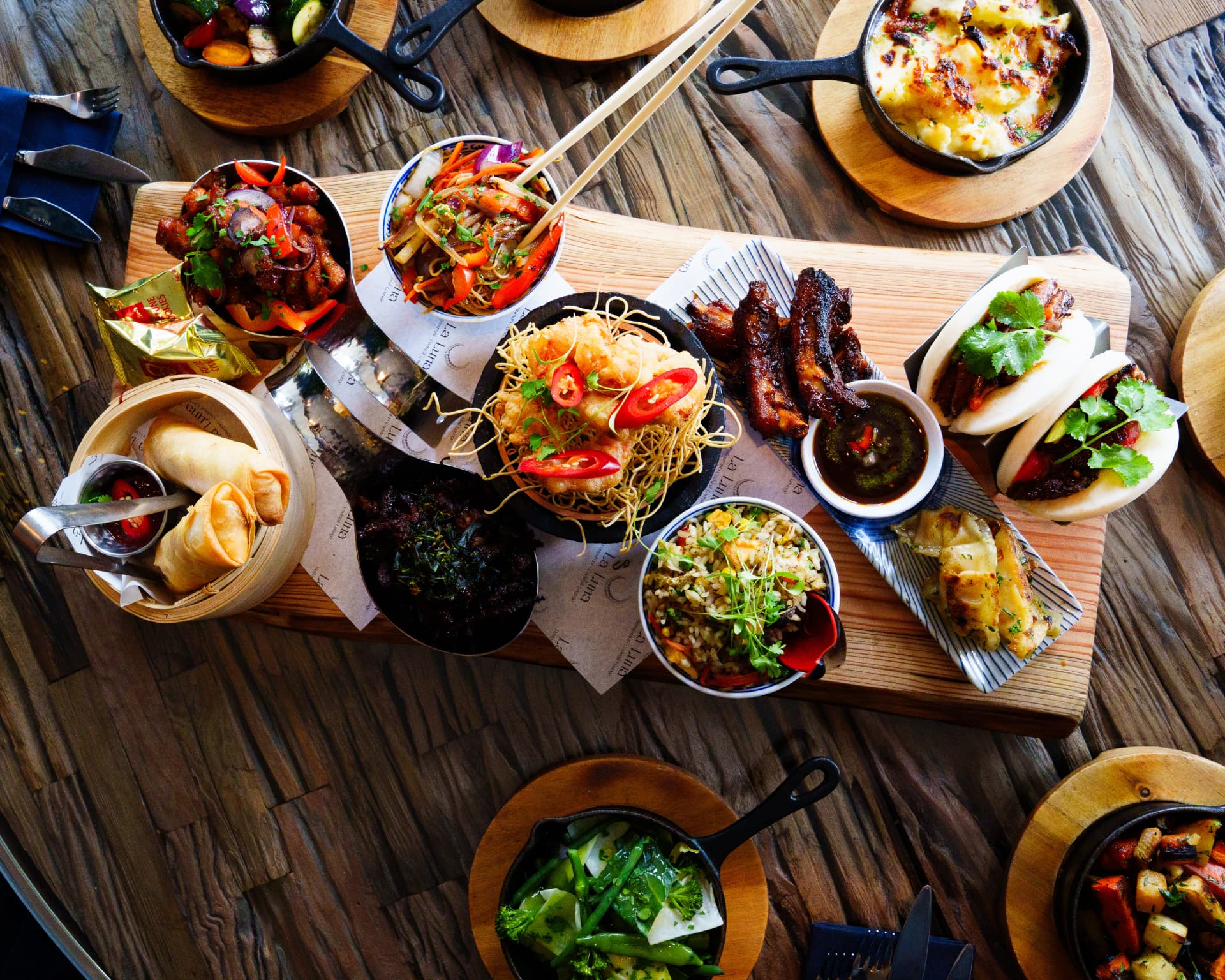 Asian sharing platter spread with bao buns, ribs, spring rolls and noodles